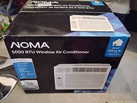 Front of sealed retail box showing NOMA 5000 BTU Window Air Conditioner image and specs