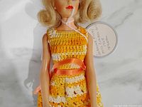 Front view of doll showing crocheted dress and ribbon belt