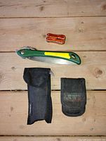 Overall view: folding saw, orange mini multi-tool, two black pouches