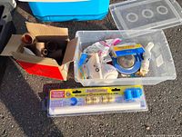Group shot showing box of copper fittings, clear bin with tape, strainer and repair kit