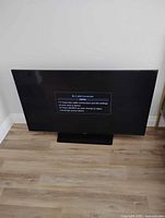 Front view of Samsung 58" TV powered on displaying 'No Cable Connected' message on stand