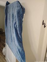 Full view of blue heated blanket draped over door