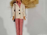 Front view of Barbie doll in cream jacket and pink pants
