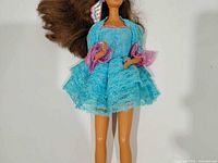 Full view of Barbie doll wearing turquoise lace dress and blue shoes