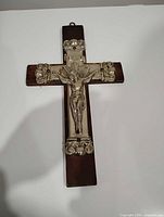 Full view of crucifix front showing wood backing, metal corpus, INRI plaque, hanging loop