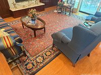 Full view of rug in room setting showing red field and blue border