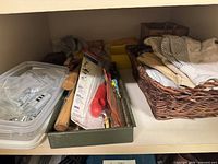 Shelf showing plastic box of fasteners, tray with tools, wicker basket with gloves