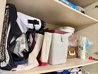 Shelf showing tote bags, cooler, cups, lids