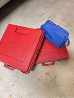 two closed red hard cases and blue fabric pouch