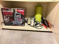 Shelf with boxed Craftsman blower/vac, cords, hand saws, jug