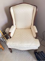 Front view of cream wingback chair showing upholstery, cushion and wood frame