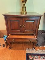Front view showing cabinet doors, drawer, and cabriole legs