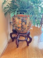 Planter with faux plant on carved wood stand