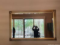 Full view of rectangular gilded mirror hung on wall