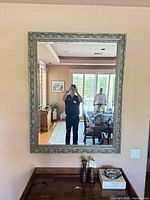 Full frontal view of ornate silver wall mirror mounted above console