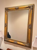 Full view of rectangular gilt wall mirror mounted on wall