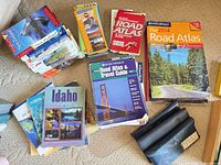 Overview of assorted travel books and atlases spread on carpet