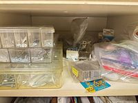 Shelf holding organizer boxes filled with screws, bags of hardware, sealant tube visible
