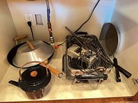 Group shot of teapot, wok, pan lid, electric grill roaster, skewers, rack, cords