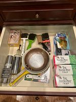 Drawer overview showing all items including saucepan, sprayer, brushes, pest traps