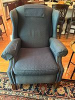 Front view of first blue patterned wingback chair showing upholstery, arms, cushion, legs