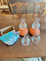 pair of assembled glass and terracotta candle holders, spare glass chimneys, bag of tealights