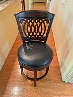 Front view of one stool showing faux leather seat, decorative backrest