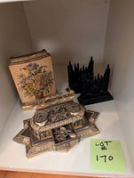 Group shot of brass inkwell, floral book box, and two black cathedral bookends
