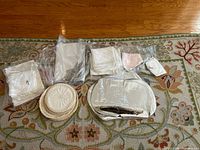 All items spread on rug: doilies, bagged linens, oval pieces