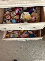 Drawer view showing assortment of dolls, puppet head and toys