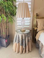 Skirted pedestal stool with glass top beside bed