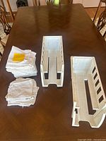 Stacked white cotton cloths and two white vented plastic holders on table