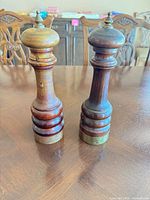 Front view of pepper mill and salt shaker showing wood grain, brass bases and finials