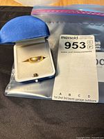 Ring in open presentation box beside lot card