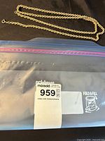 Full view of rope chain necklace alongside labeled storage bag