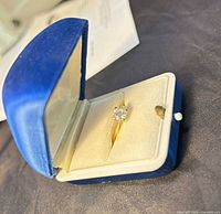 Ring in blue presentation box, showing solitaire diamond