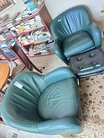 Two green leather barrel chairs and ottoman showing overall style and condition