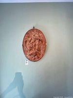 Wall-mounted oval terracotta plaque viewed at distance
