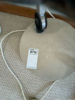 Round stone base, wheels on underside, power cord visible