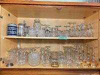 Cabinet shelves showing mixed crystal and glass stemware, bowls, decanter, steins