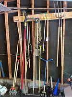 Overall view of long-handle garden tools hanging on wall, plus rotary cultivator