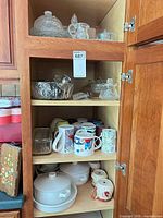 Cabinet view showing casseroles, mugs, glassware