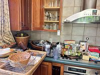 Overview of countertop with mixing bowls, glasses, utensils, wooden bowl, decanter, glass pitcher