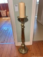 Full view of brass floor candlestick with candle in place