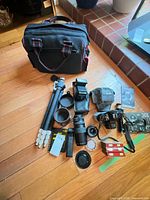 All items laid out including camera, lenses, flash, tripods, accessories, bag