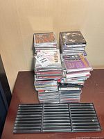 stack of CDs in jewel cases, black plastic insert in foreground