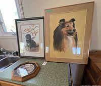 Overall view of two framed prints and framed plate on counter