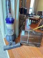 Dyson vacuum standing next to closed Singer wooden case