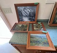 Group of four framed oil paintings displayed on countertop