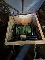 open hose reel box showing coiled green hose on reel